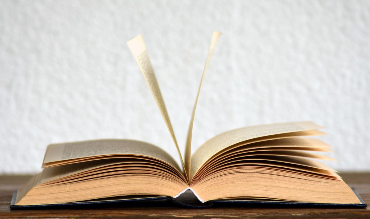 Hands turning pages in a bound volume
